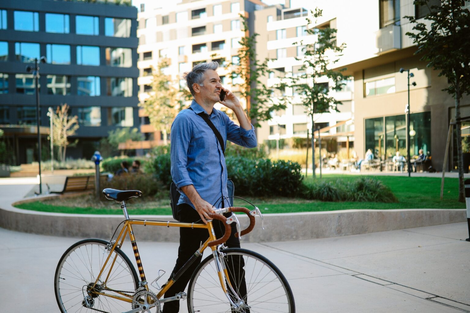 Mann parkt sein Fahrrad vor dem Büro und nutzt sein Smartphone.
