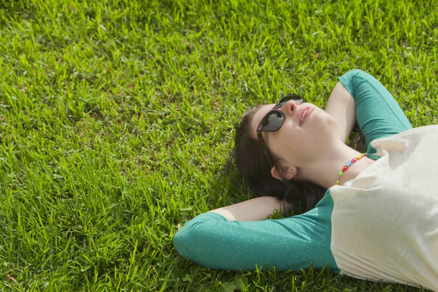 Junge Frau genießt eine Pause im Frühling und liegt entspannt im Gras